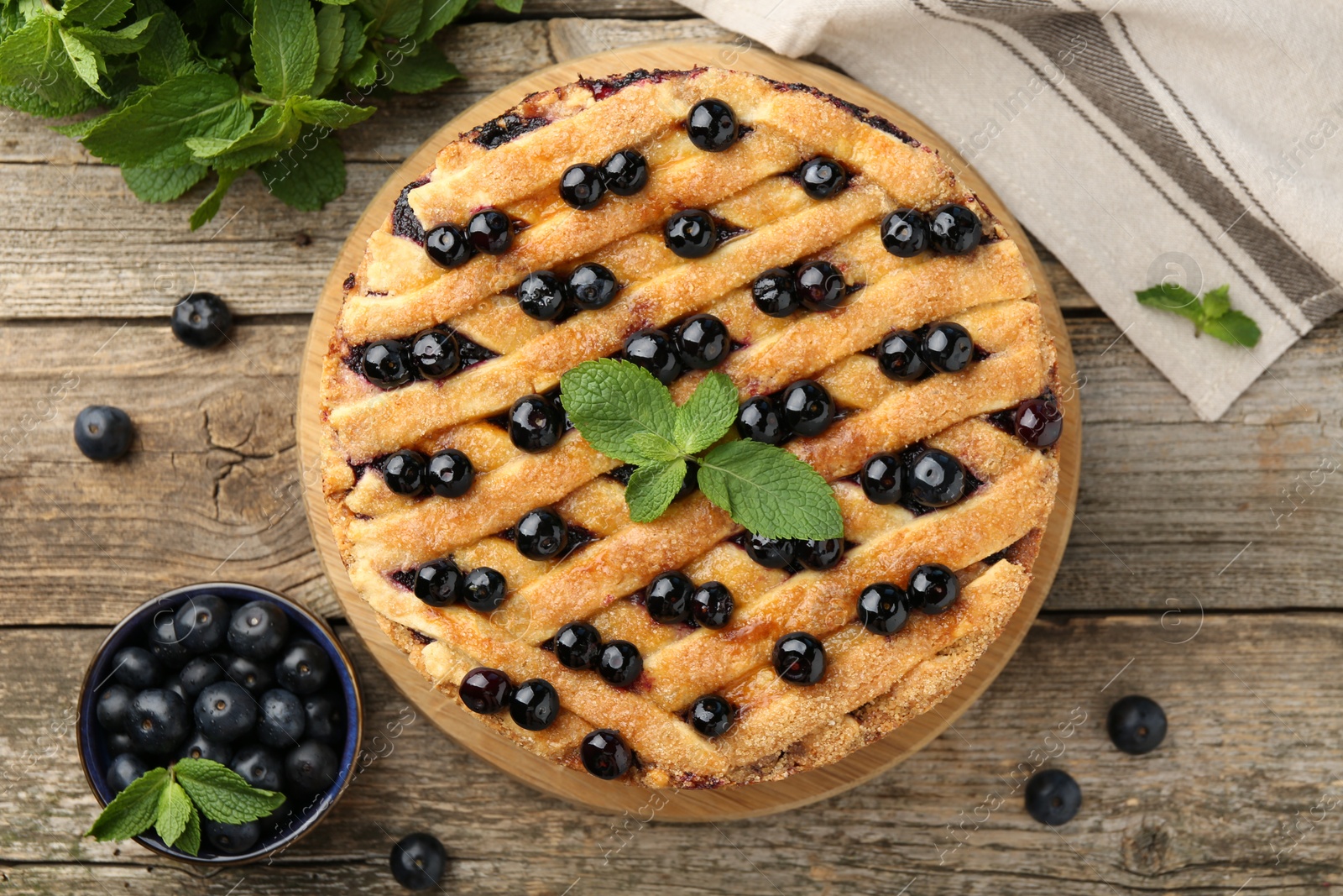 Photo of Delicious homemade blueberry pie with mint and fresh berries on wooden table, top view