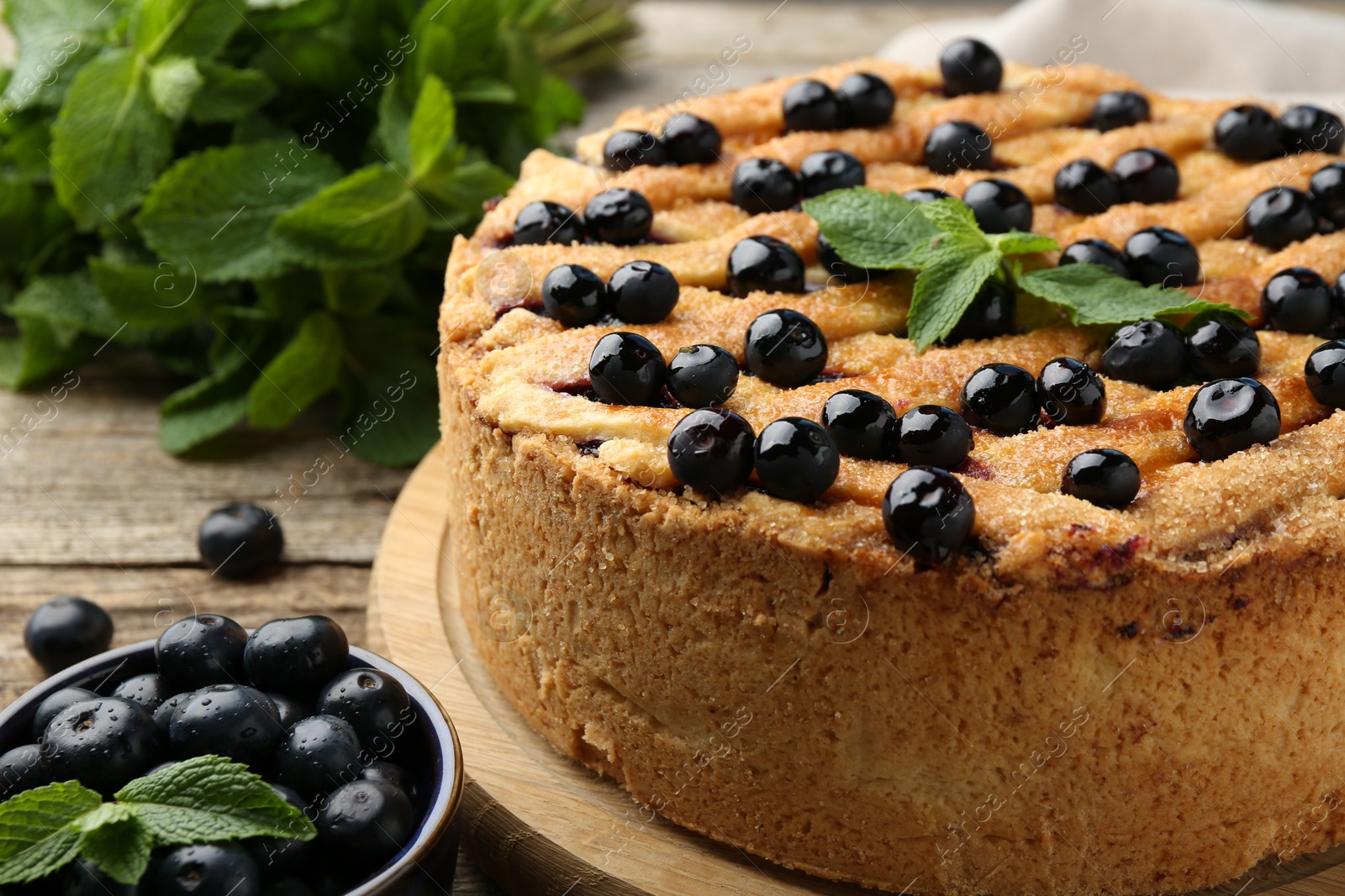 Photo of Delicious homemade blueberry pie with mint and fresh berries on wooden table, closeup