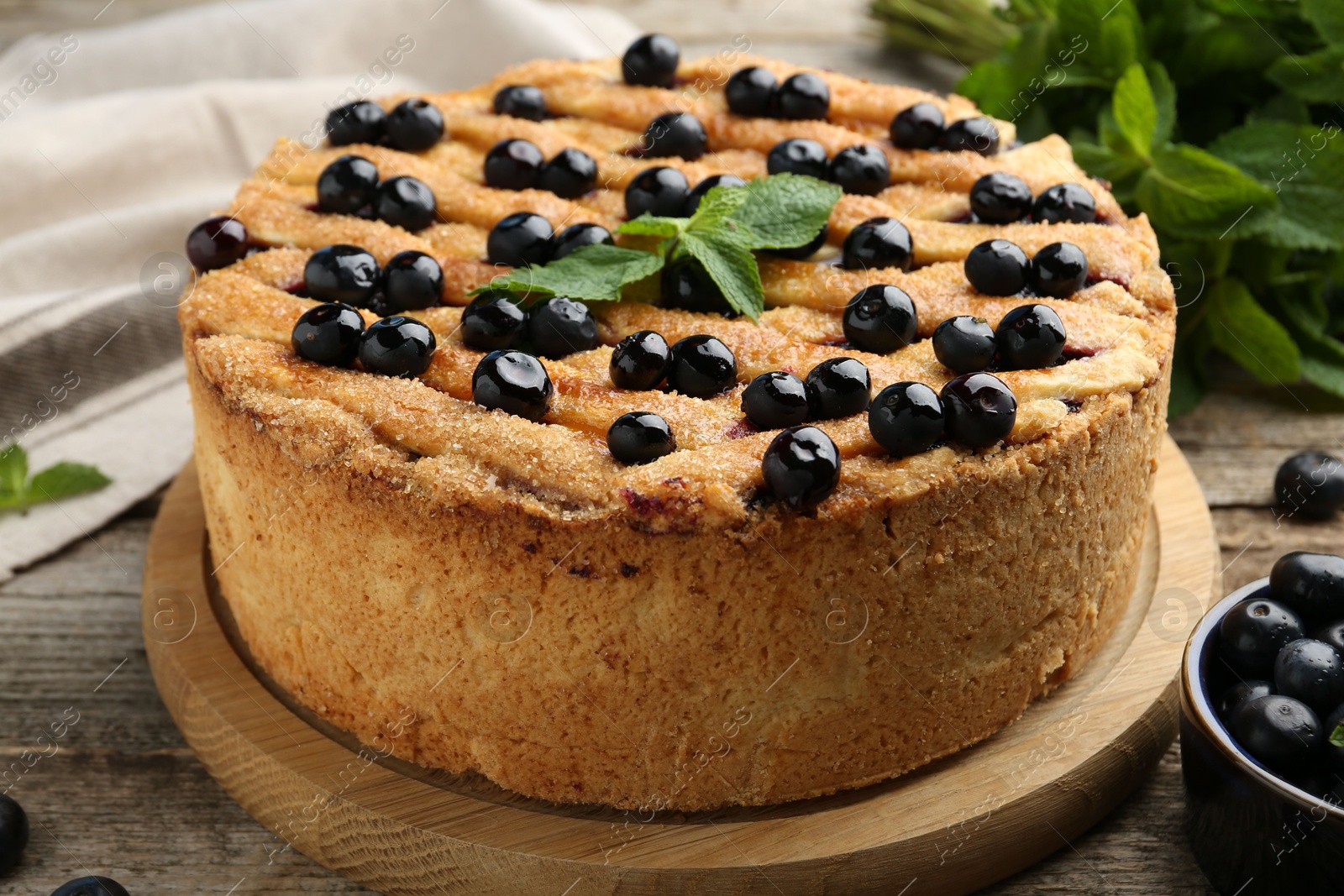 Photo of Delicious homemade blueberry pie with mint and fresh berries on wooden table, closeup