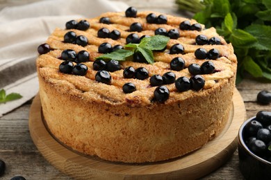 Photo of Delicious homemade blueberry pie with mint and fresh berries on wooden table, closeup