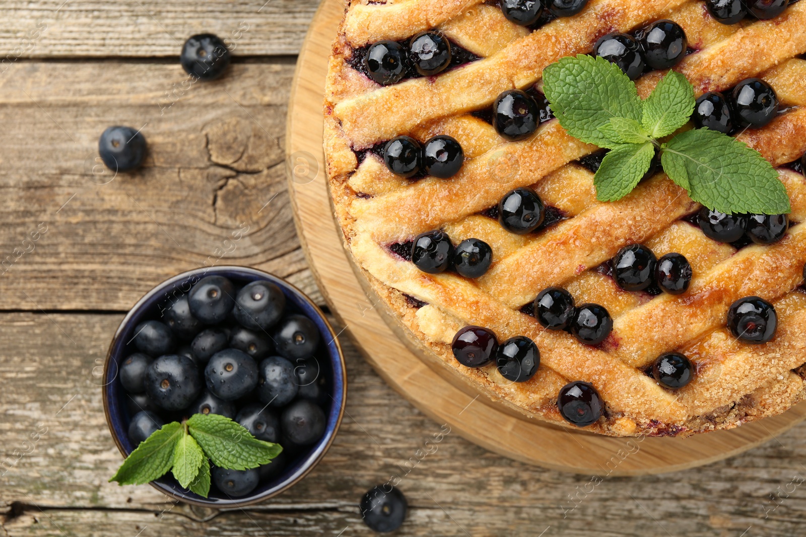 Photo of Delicious homemade blueberry pie with mint and fresh berries on wooden table, top view