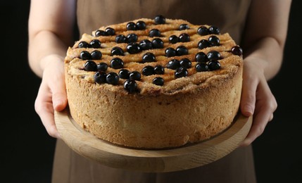 Photo of Woman with delicious homemade blueberry pie on black background, closeup