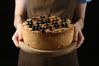 Photo of Woman with delicious homemade blueberry pie on black background, closeup