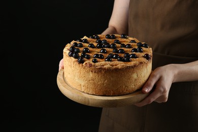 Photo of Woman with delicious homemade blueberry pie on black background, closeup