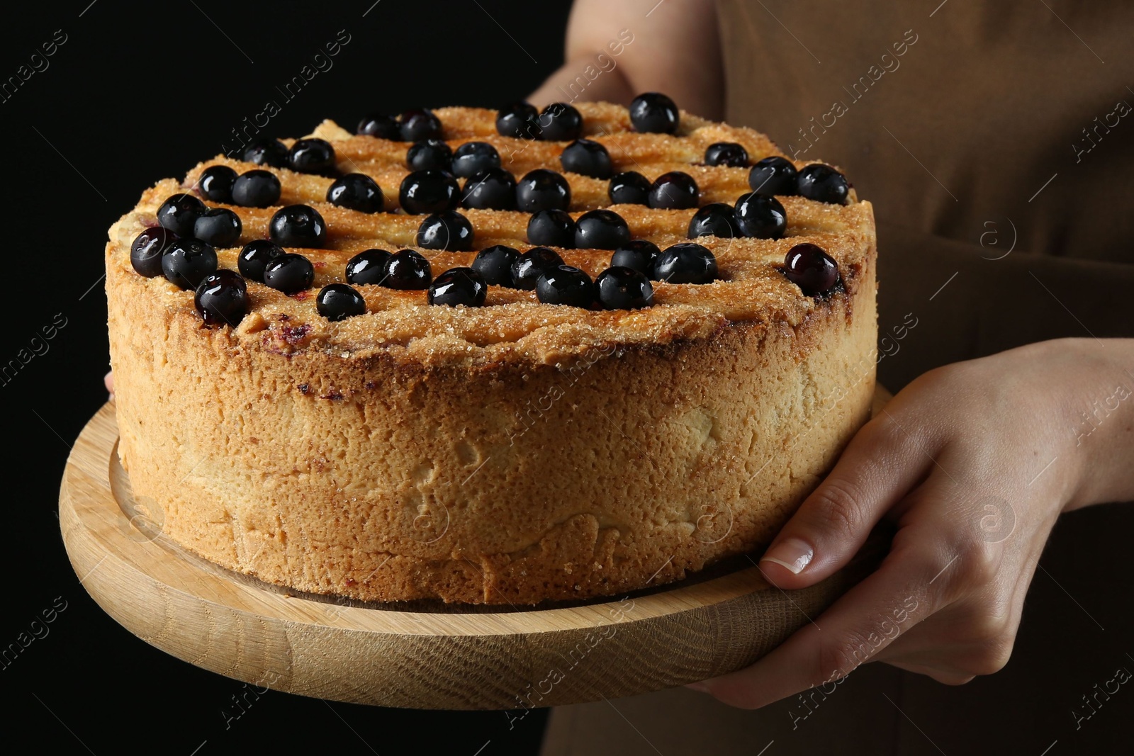 Photo of Woman with delicious homemade blueberry pie on black background, closeup