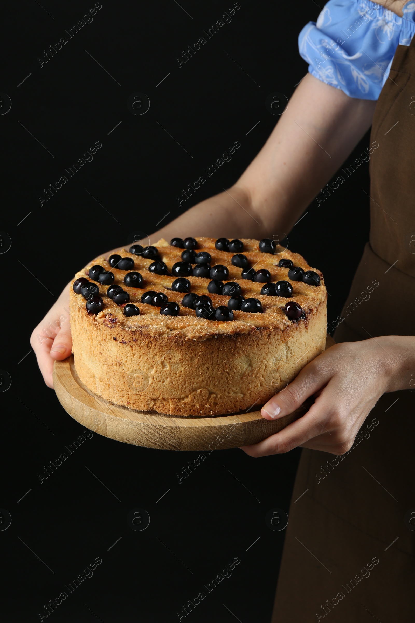 Photo of Woman with delicious homemade blueberry pie on black background, closeup