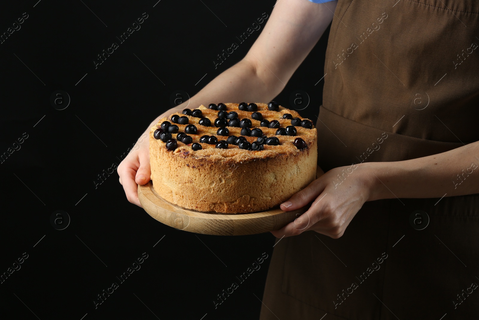 Photo of Woman with delicious homemade blueberry pie on black background, closeup