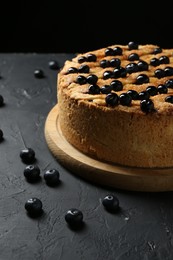 Photo of Delicious homemade blueberry pie and fresh berries on black table