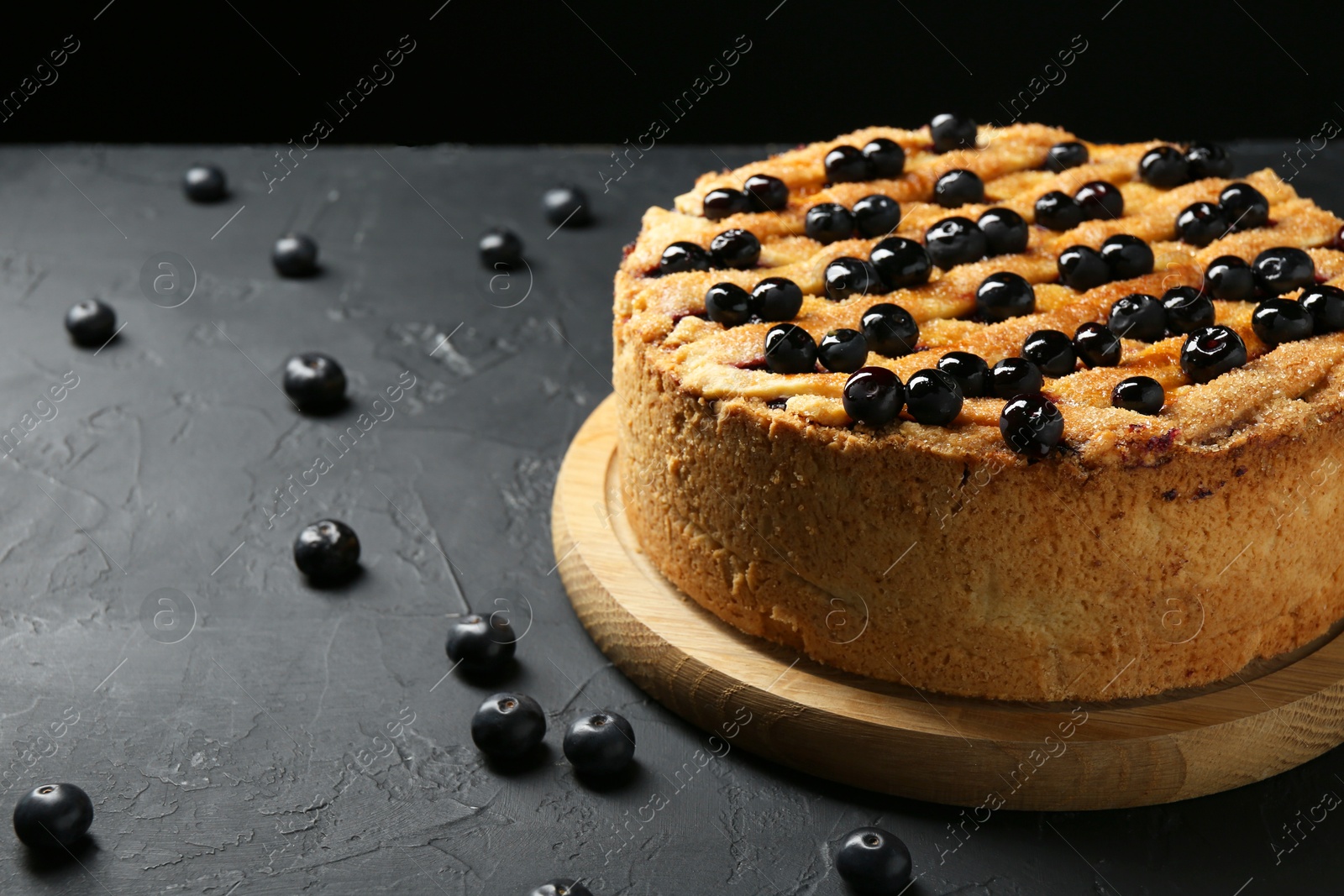 Photo of Delicious homemade blueberry pie and fresh berries on black table