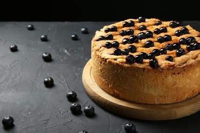 Photo of Delicious homemade blueberry pie and fresh berries on black table