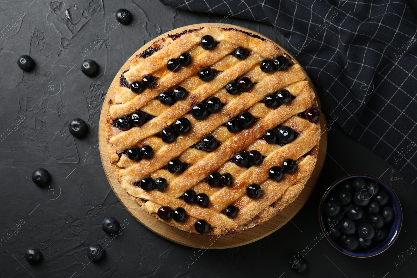 Photo of Delicious homemade blueberry pie and fresh berries on black table, top view