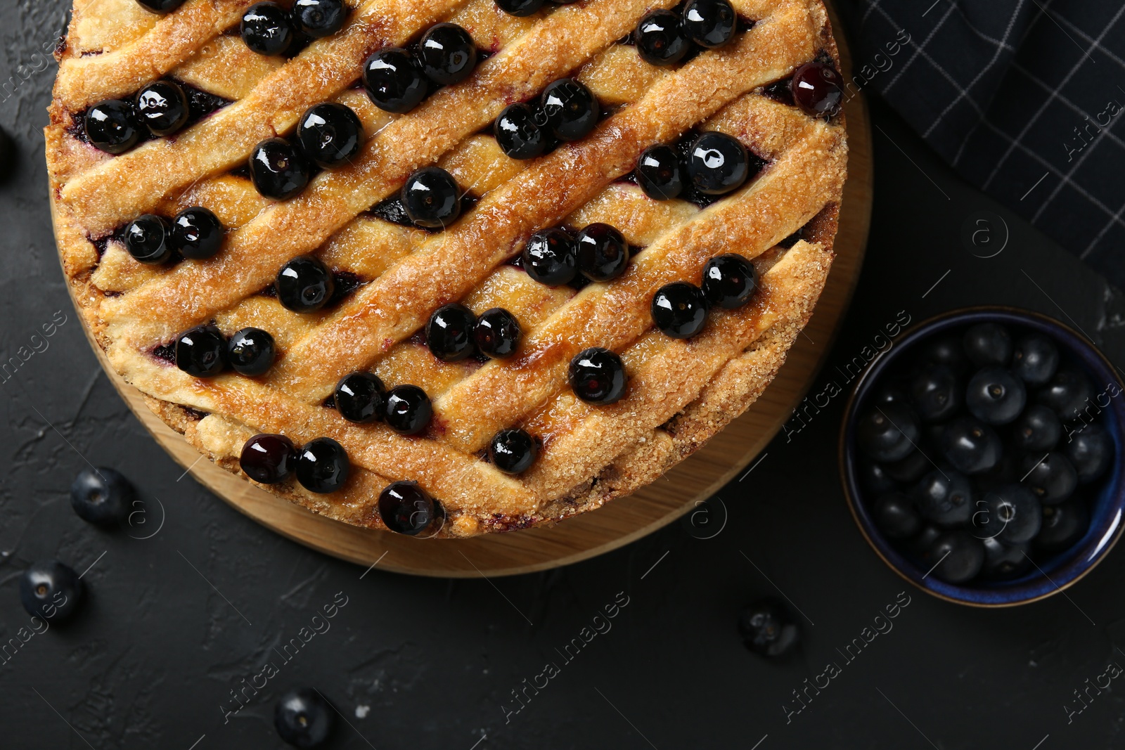 Photo of Delicious homemade blueberry pie and fresh berries on black table, top view