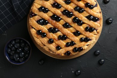 Photo of Delicious homemade blueberry pie and fresh berries on black table, top view