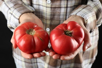 Woman holding fresh ripe tomatoes on black background, closeup