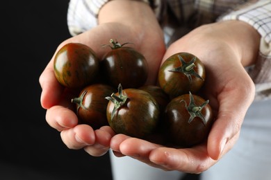 Woman holding fresh ripe tomatoes on black background, closeup