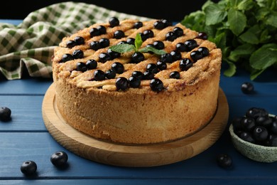 Photo of Delicious homemade blueberry pie with mint and fresh berries on blue wooden table