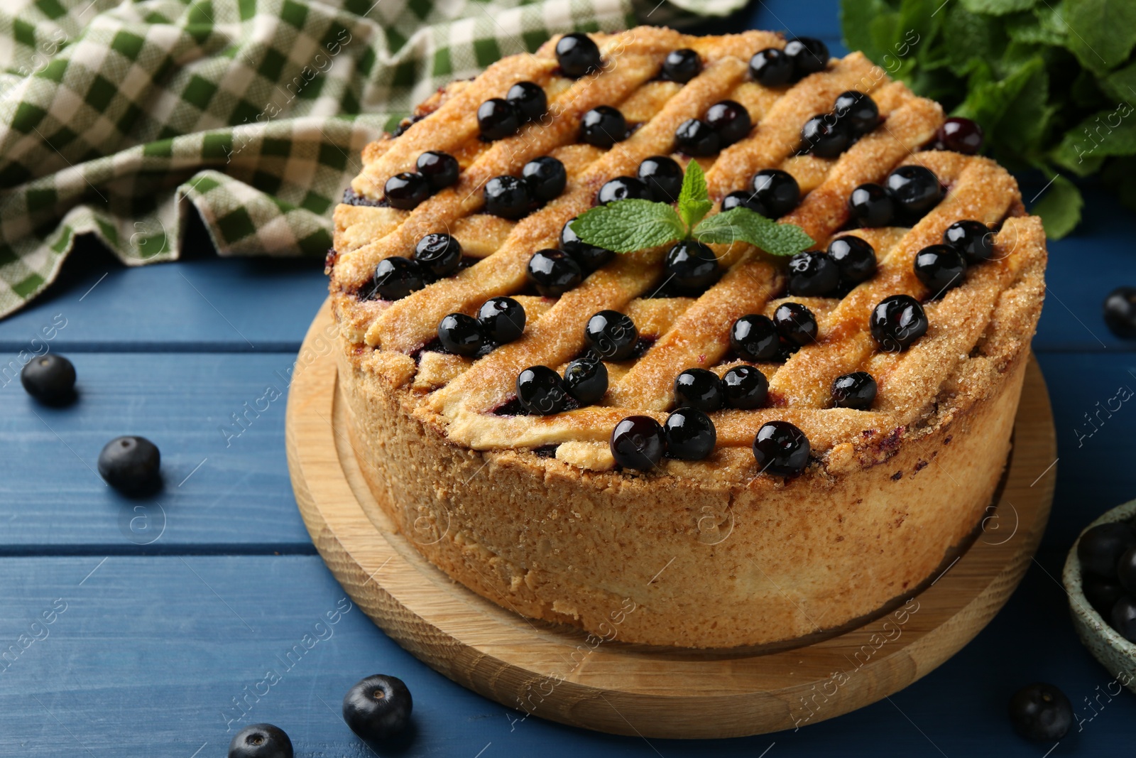 Photo of Delicious homemade blueberry pie with mint and fresh berries on blue wooden table, closeup