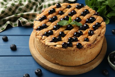 Photo of Delicious homemade blueberry pie with mint and fresh berries on blue wooden table, closeup