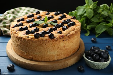 Photo of Delicious homemade blueberry pie with mint and fresh berries on blue wooden table, closeup