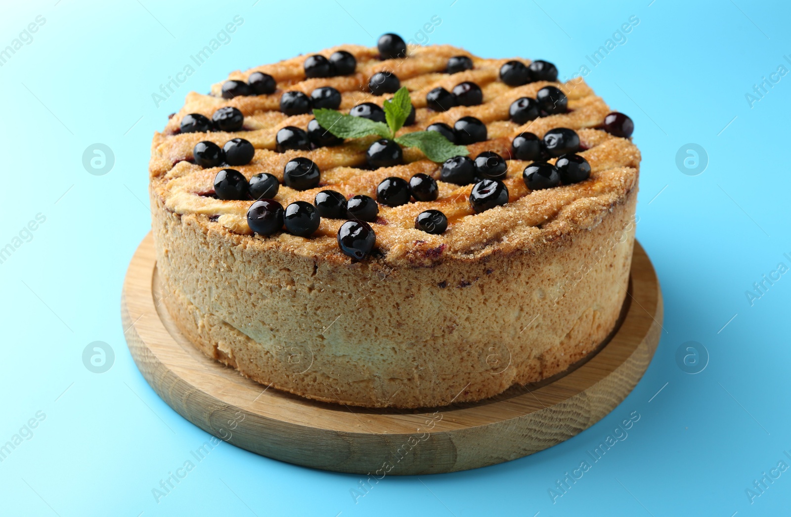 Photo of Delicious homemade blueberry pie with mint on light blue background, closeup