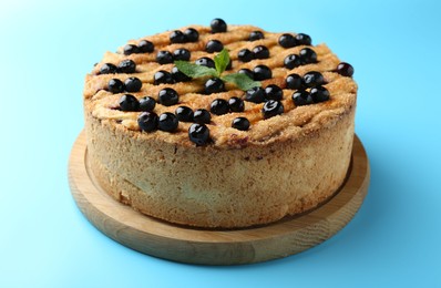 Photo of Delicious homemade blueberry pie with mint on light blue background, closeup