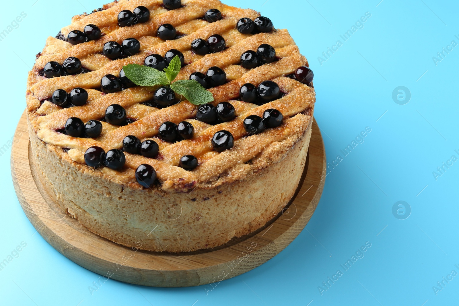 Photo of Delicious homemade blueberry pie with mint on light blue background