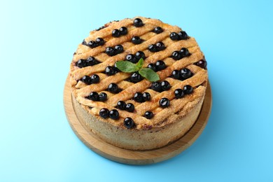 Photo of Delicious homemade blueberry pie with mint on light blue background