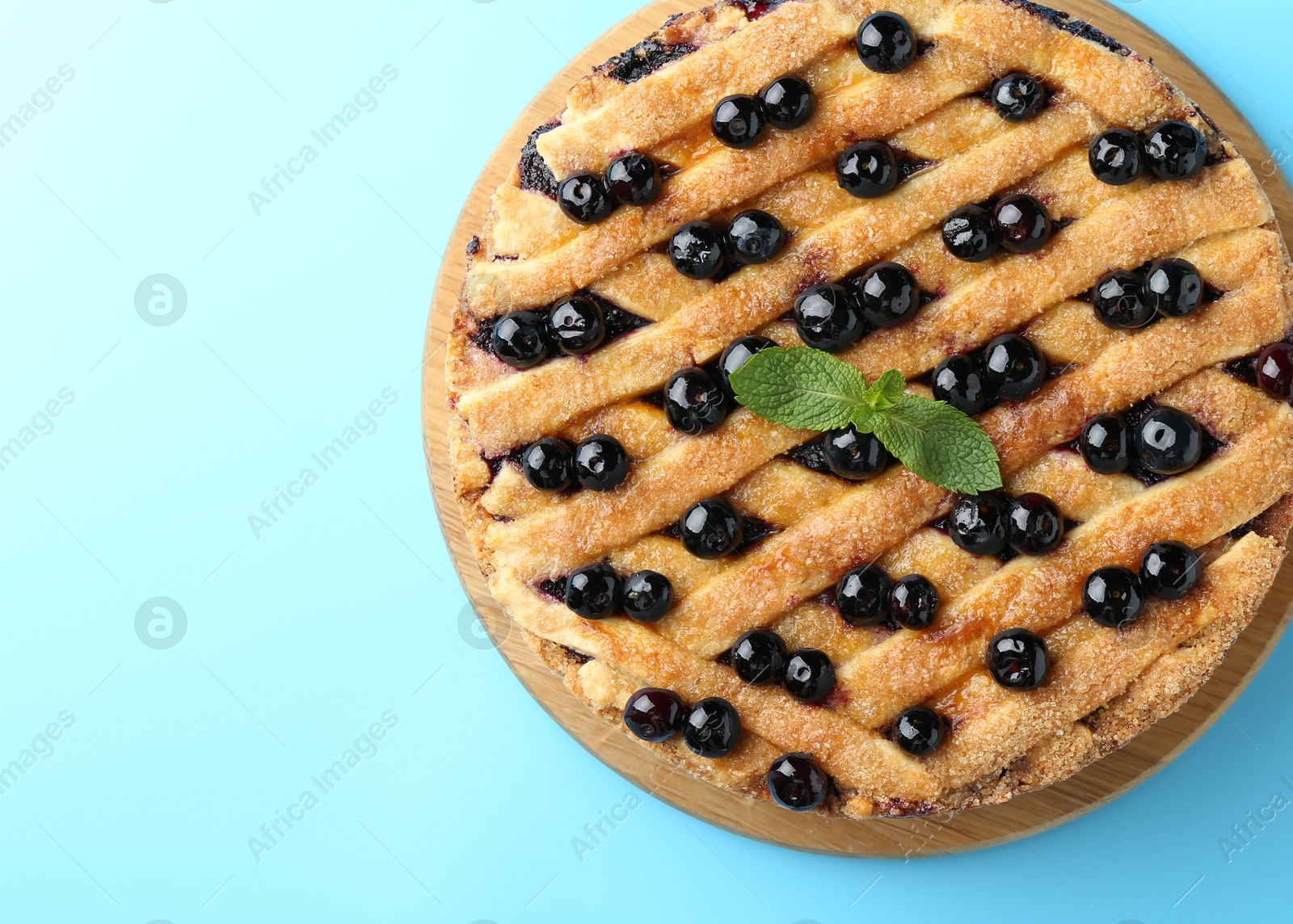 Photo of Delicious homemade blueberry pie with mint on light blue background, top view. Space for text