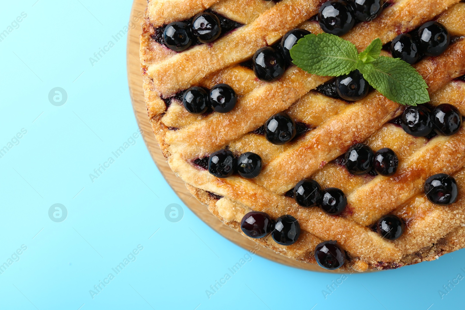 Photo of Delicious homemade blueberry pie with mint on light blue background, top view