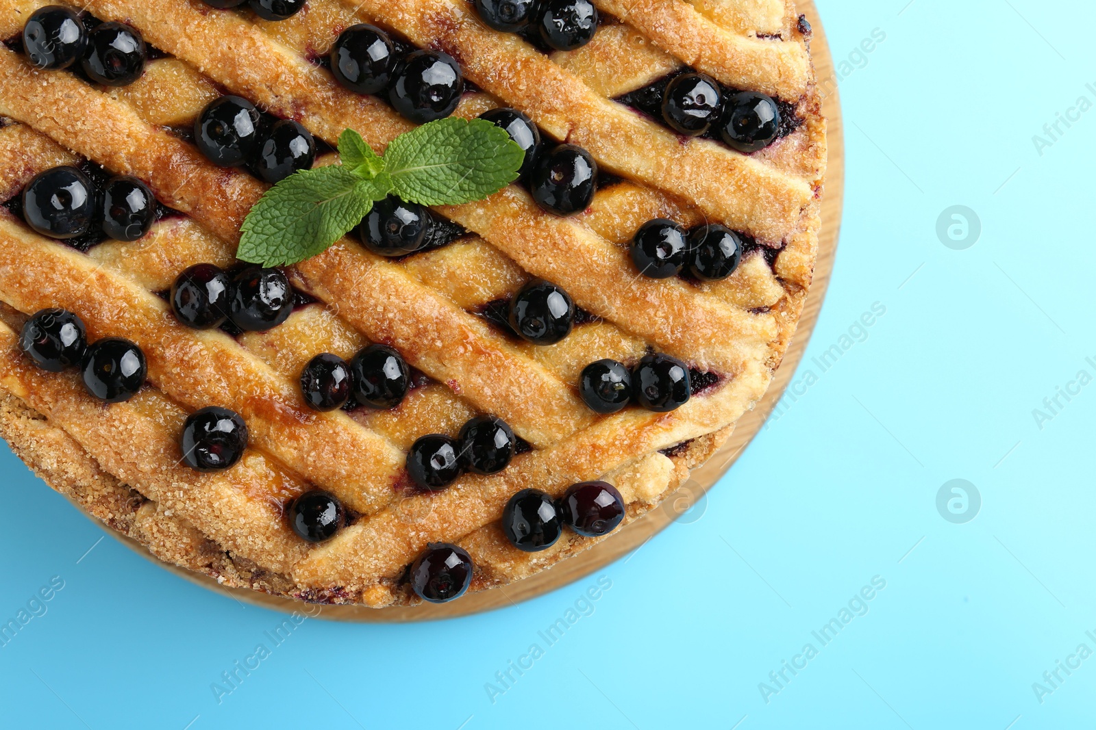 Photo of Delicious homemade blueberry pie with mint on light blue background, top view