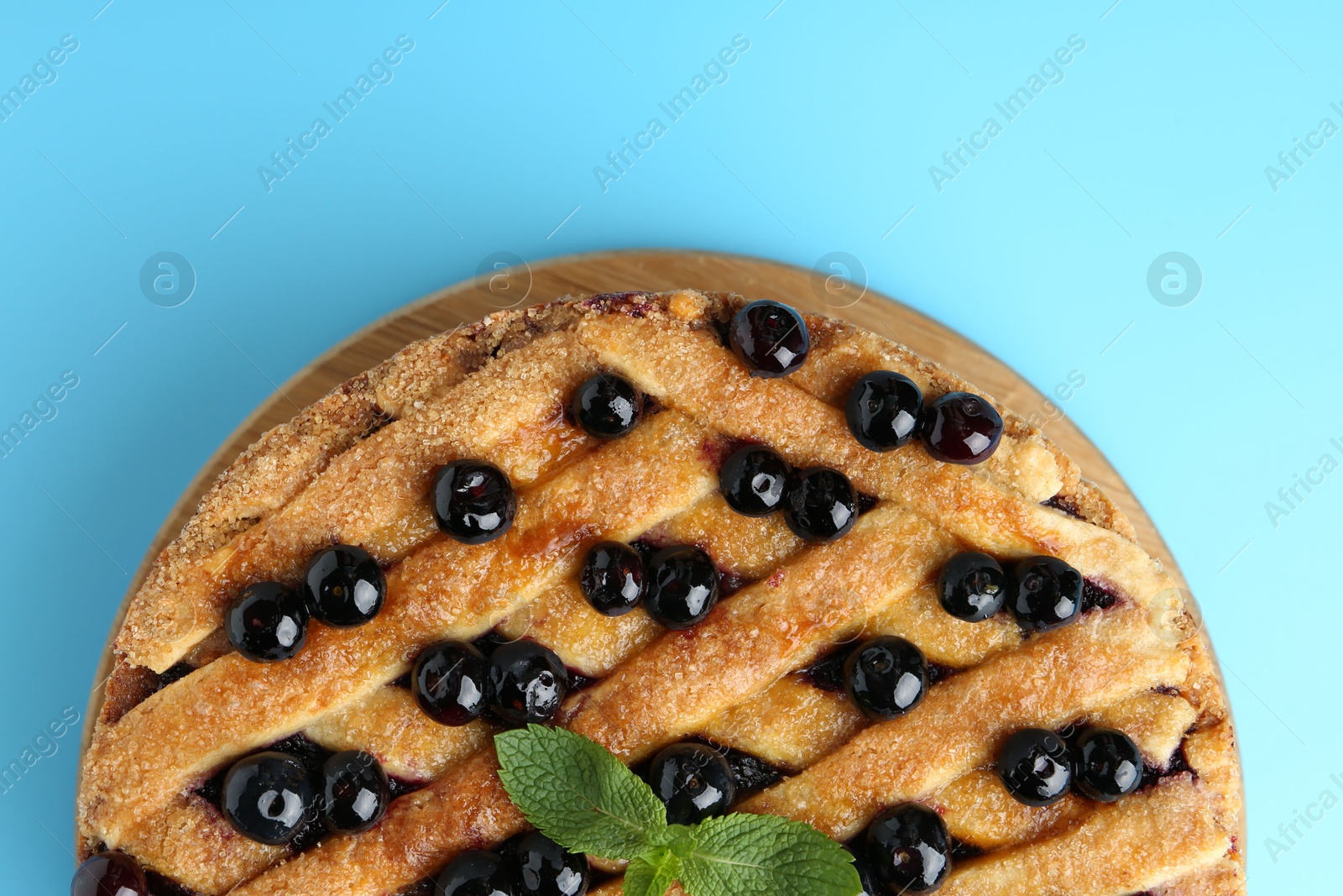 Photo of Delicious homemade blueberry pie with mint on light blue background, top view