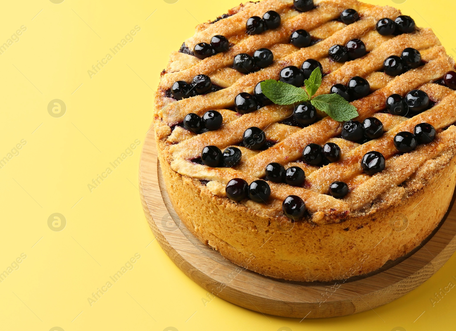 Photo of Delicious homemade blueberry pie with mint on yellow background