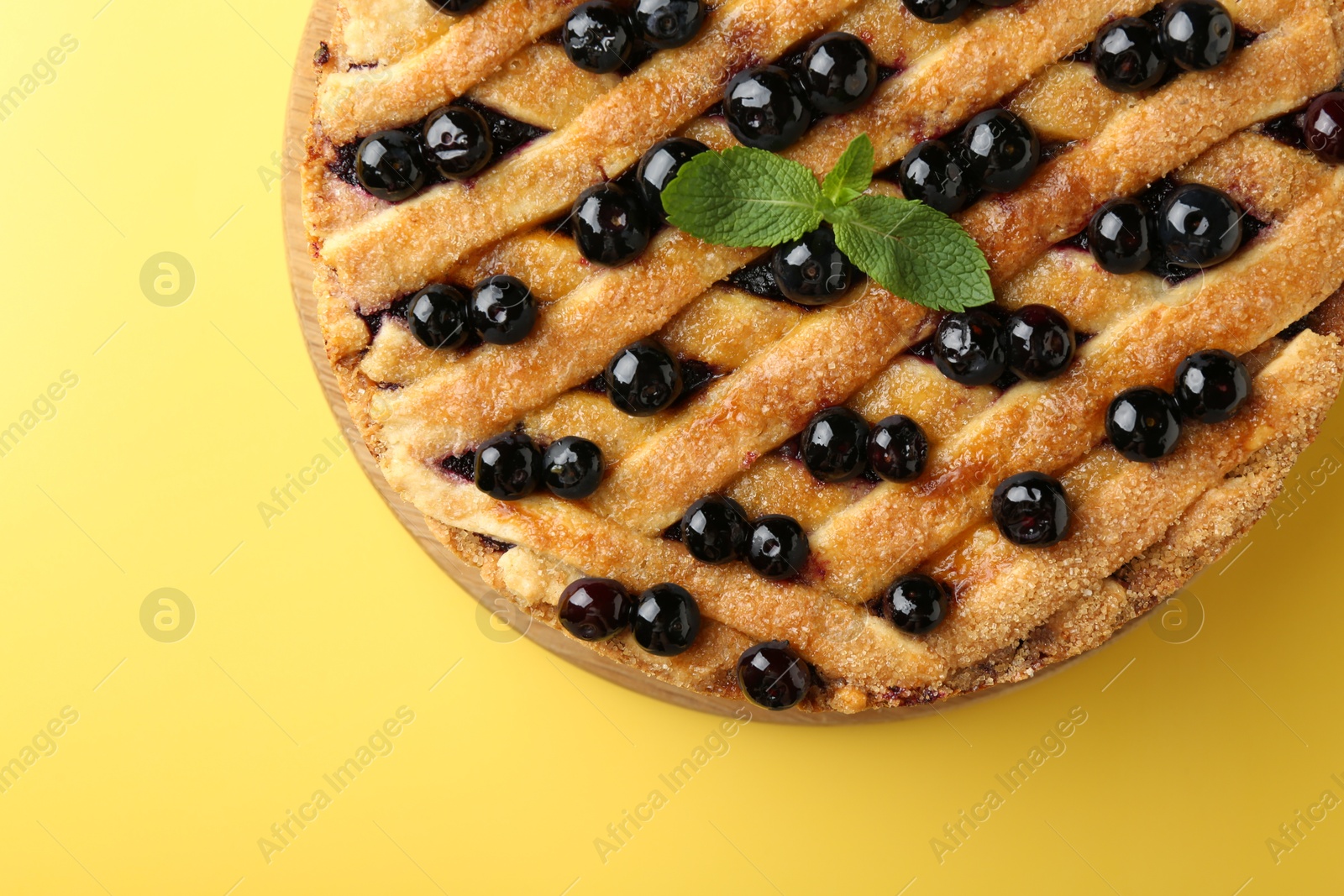 Photo of Delicious homemade blueberry pie with mint on yellow background, top view