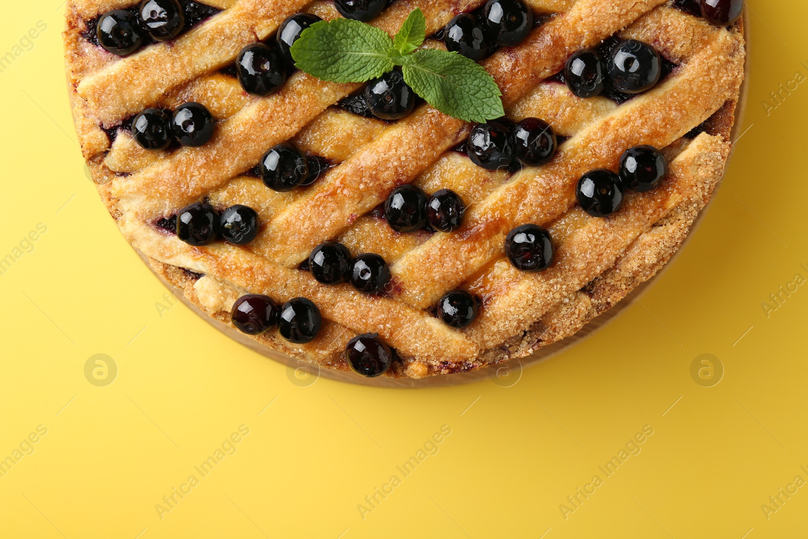 Photo of Delicious homemade blueberry pie with mint on yellow background, top view