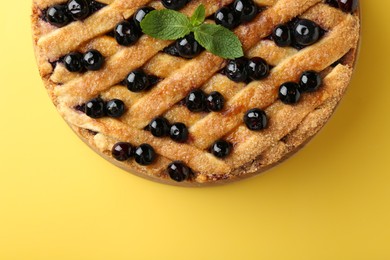 Photo of Delicious homemade blueberry pie with mint on yellow background, top view