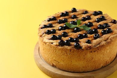 Photo of Delicious homemade blueberry pie with mint on yellow background, closeup