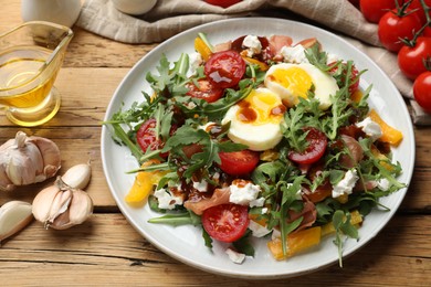 Tasty salad with arugula, egg, cheese and vegetables on wooden table, closeup