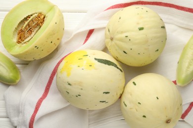 Photo of Fresh whole and cut honeydew melons on white wooden table, flat lay