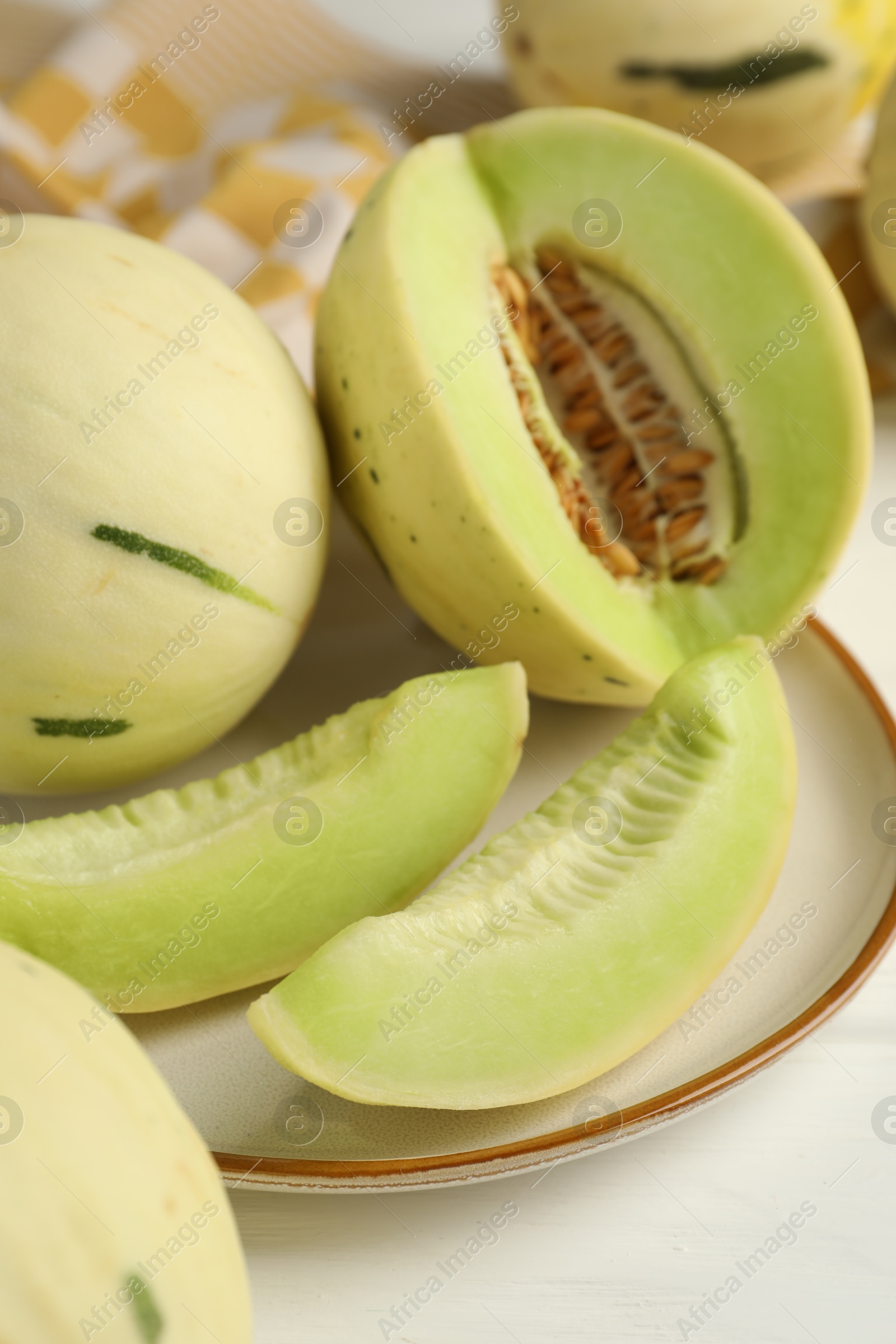 Photo of Fresh whole and cut honeydew melons on white wooden table, closeup