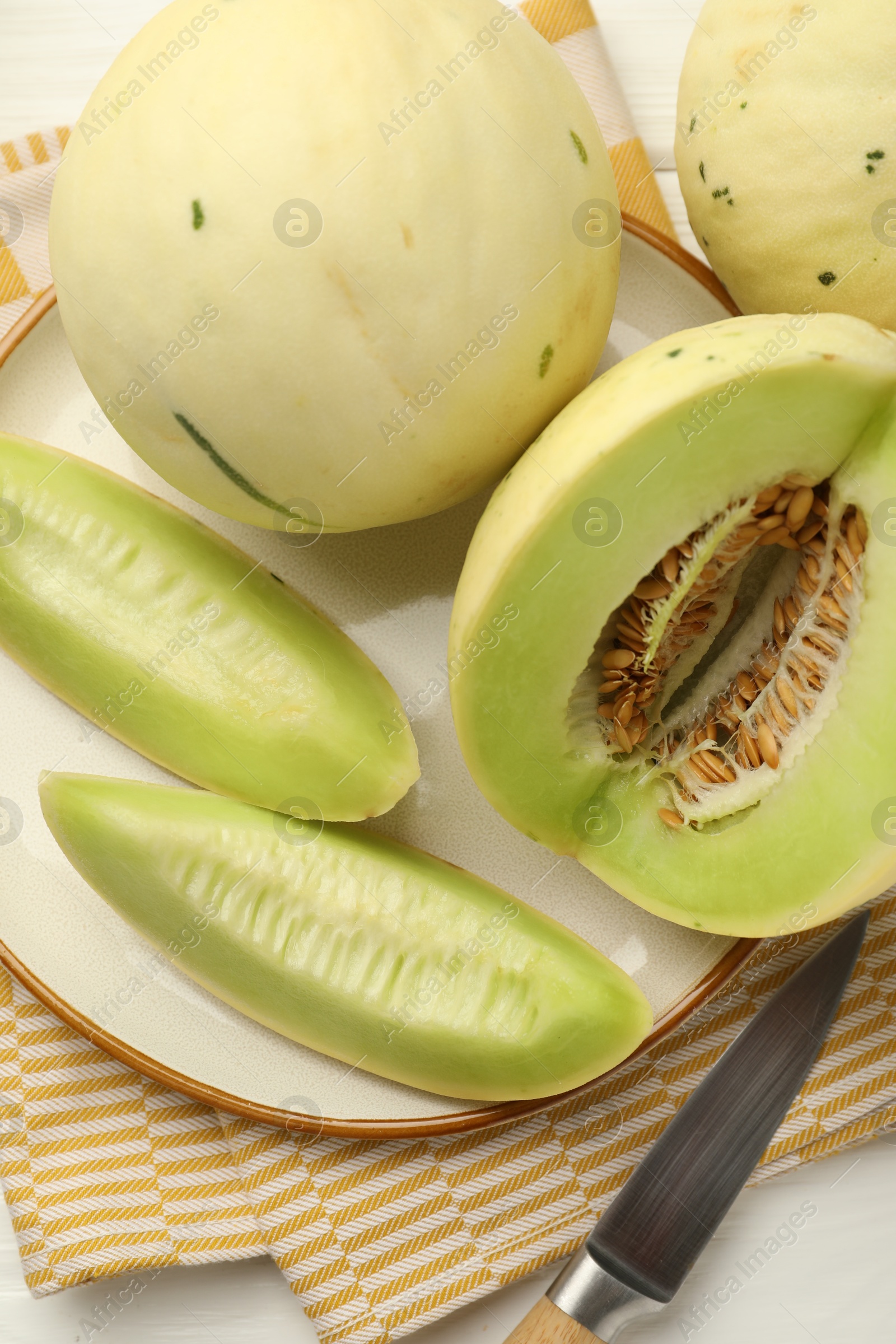 Photo of Fresh whole and cut honeydew melons on white wooden table, flat lay