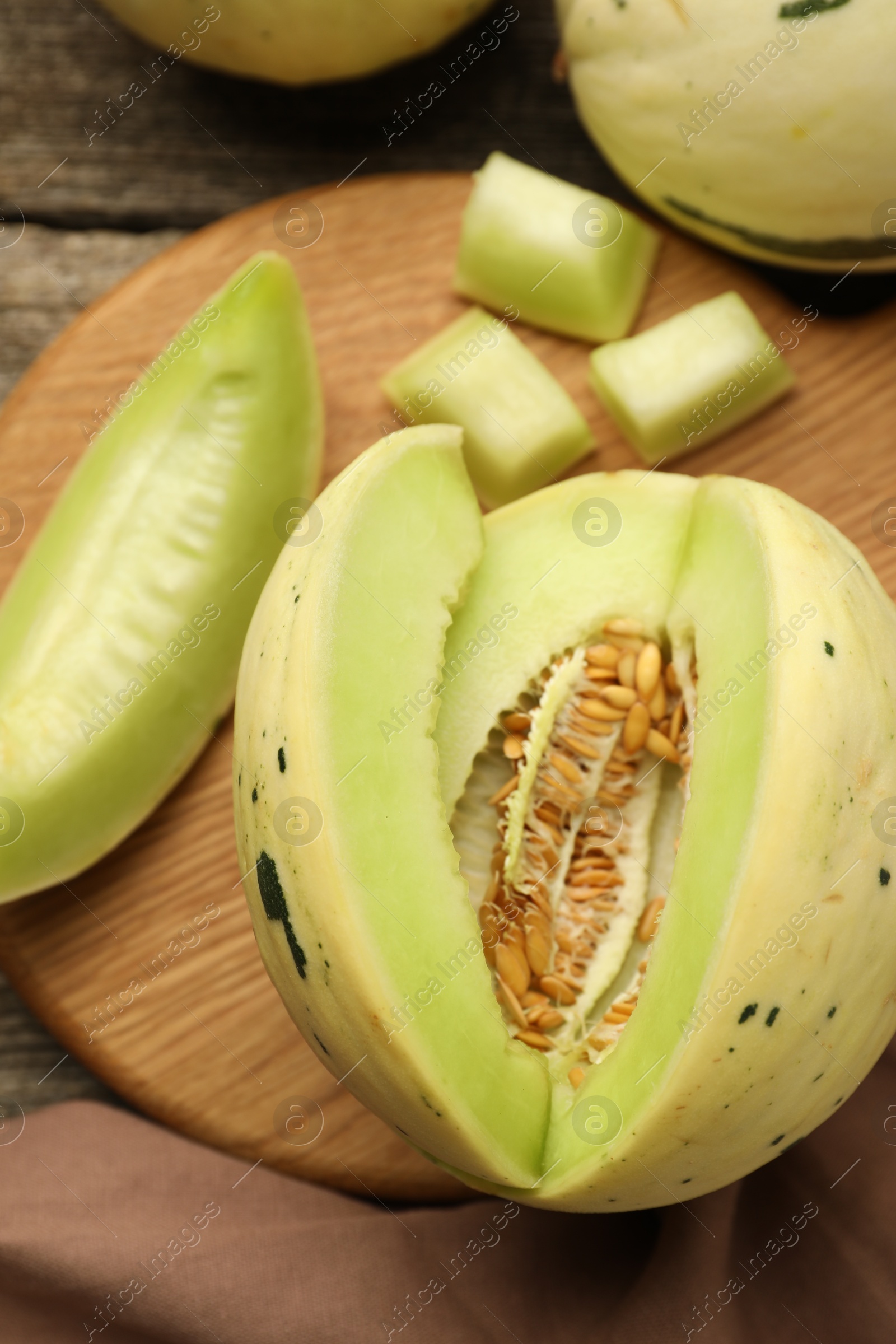 Photo of Fresh cut honeydew melon on wooden table, flat lay