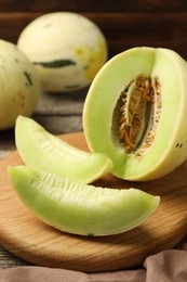 Photo of Fresh whole and cut honeydew melons on wooden table, closeup