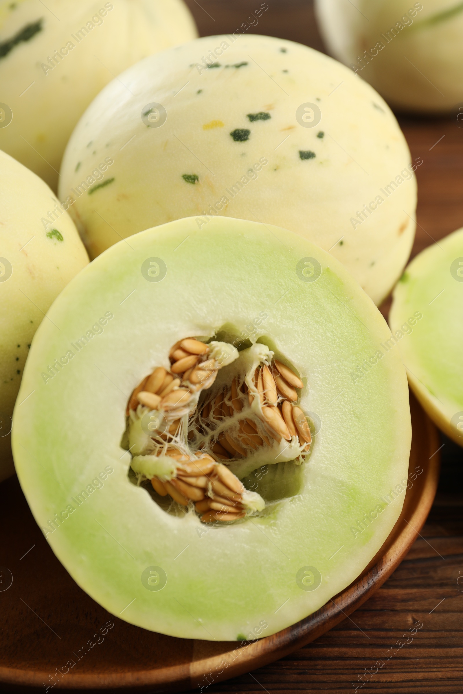 Photo of Fresh whole and cut honeydew melons on wooden table, closeup