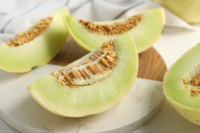 Photo of Fresh cut honeydew melon on white wooden table, closeup