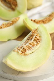 Photo of Fresh cut honeydew melon on white wooden table, closeup