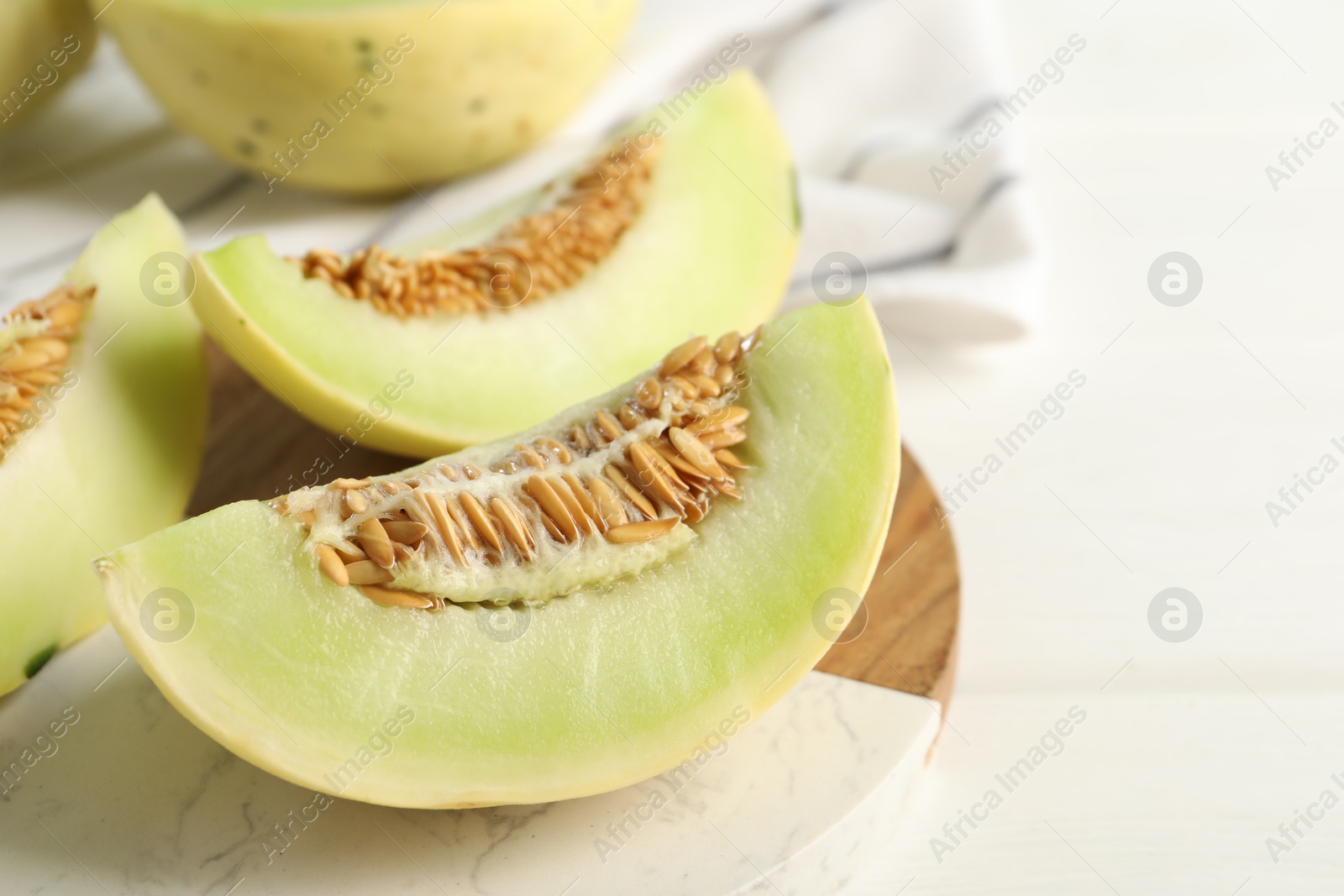 Photo of Fresh cut honeydew melon on white wooden table, closeup