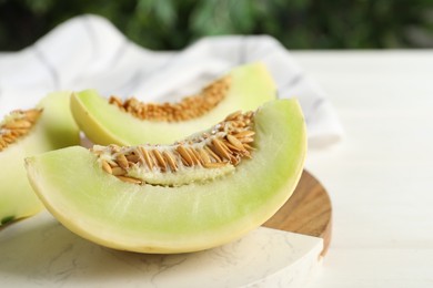 Photo of Fresh cut honeydew melon on white wooden table, closeup