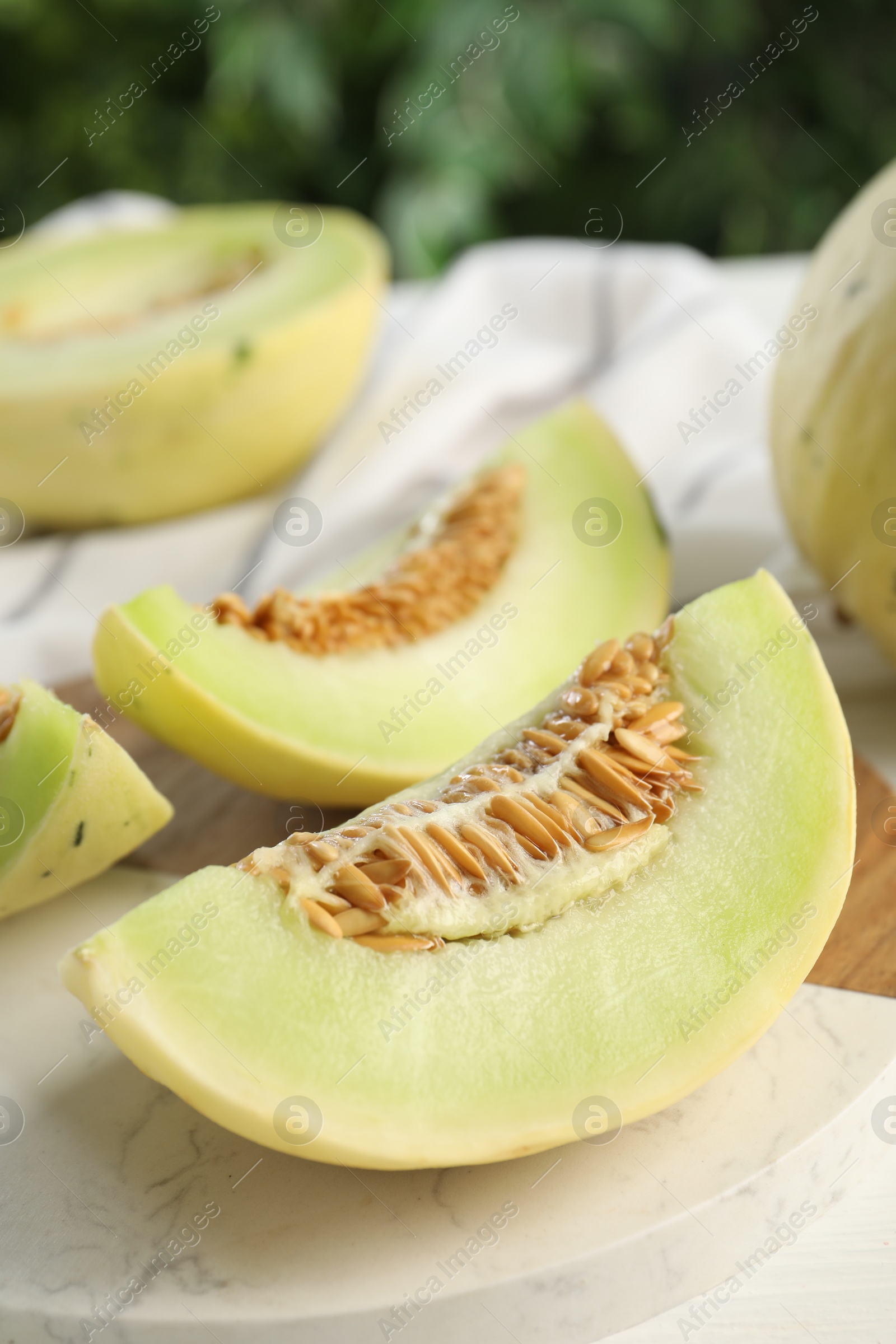 Photo of Fresh cut honeydew melon on white wooden table, closeup