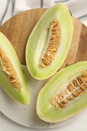 Photo of Fresh cut honeydew melon on white wooden table, top view