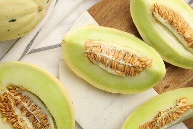 Photo of Fresh cut honeydew melons on white table, flat lay